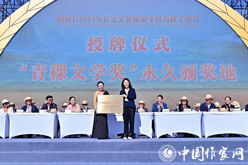 陳亞軍主編代表《民族文學(xué)》向阿壩縣授牌，紅梅部長接牌。